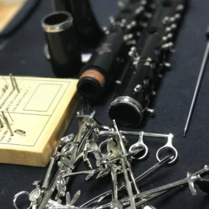Disassembled clarinet with keys and parts spread on a workbench.
