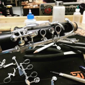 Clarinet with reassembled keys on a workbench.