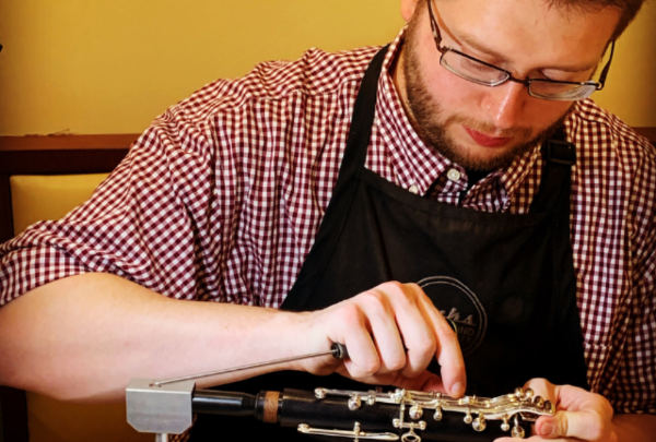 A technician adjusts the keys on a clarinet.